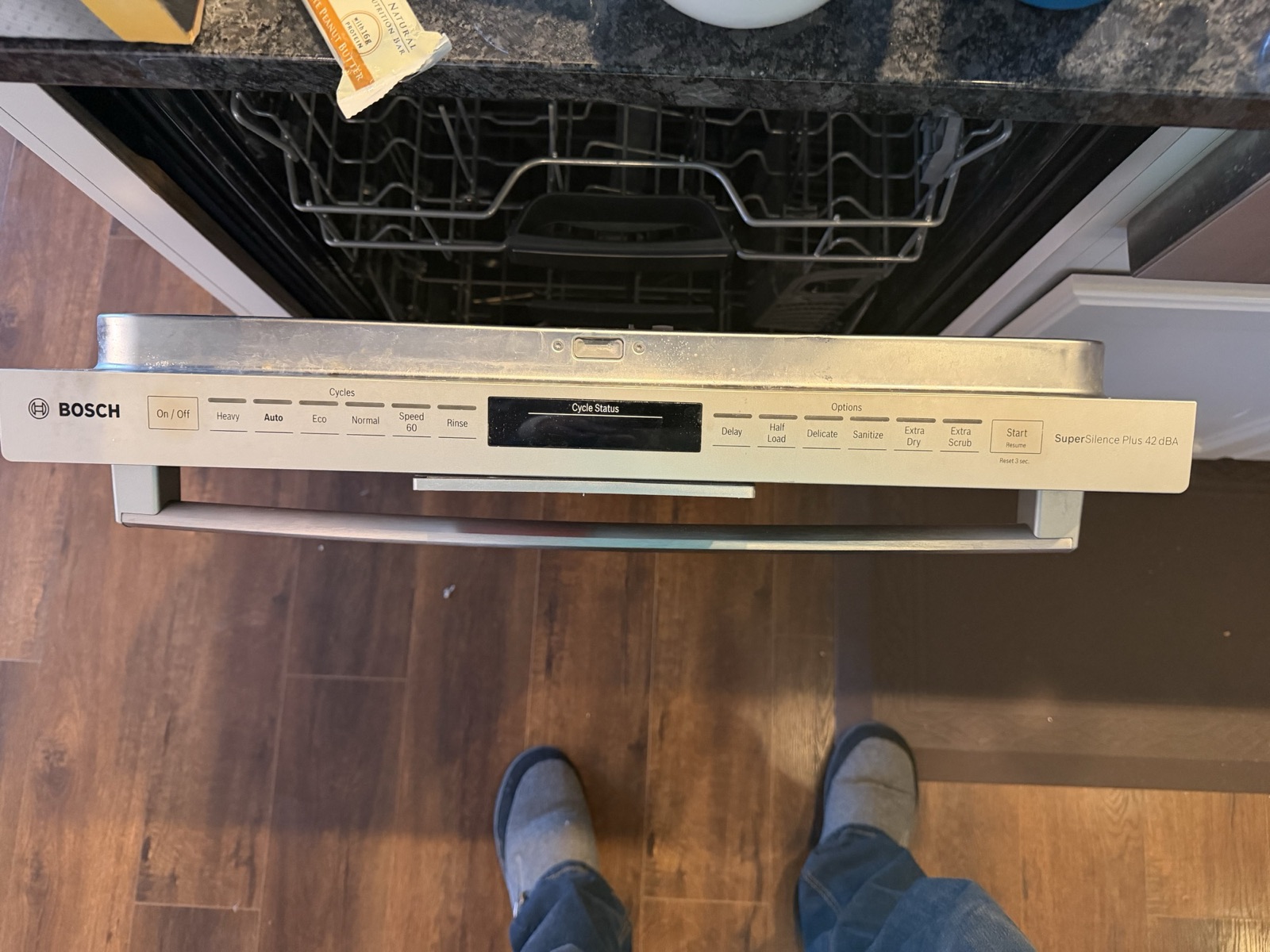 Open built-in Bosch dishwasher viewed from above, showing the full front control panel with cycle and option buttons and a bar handle.