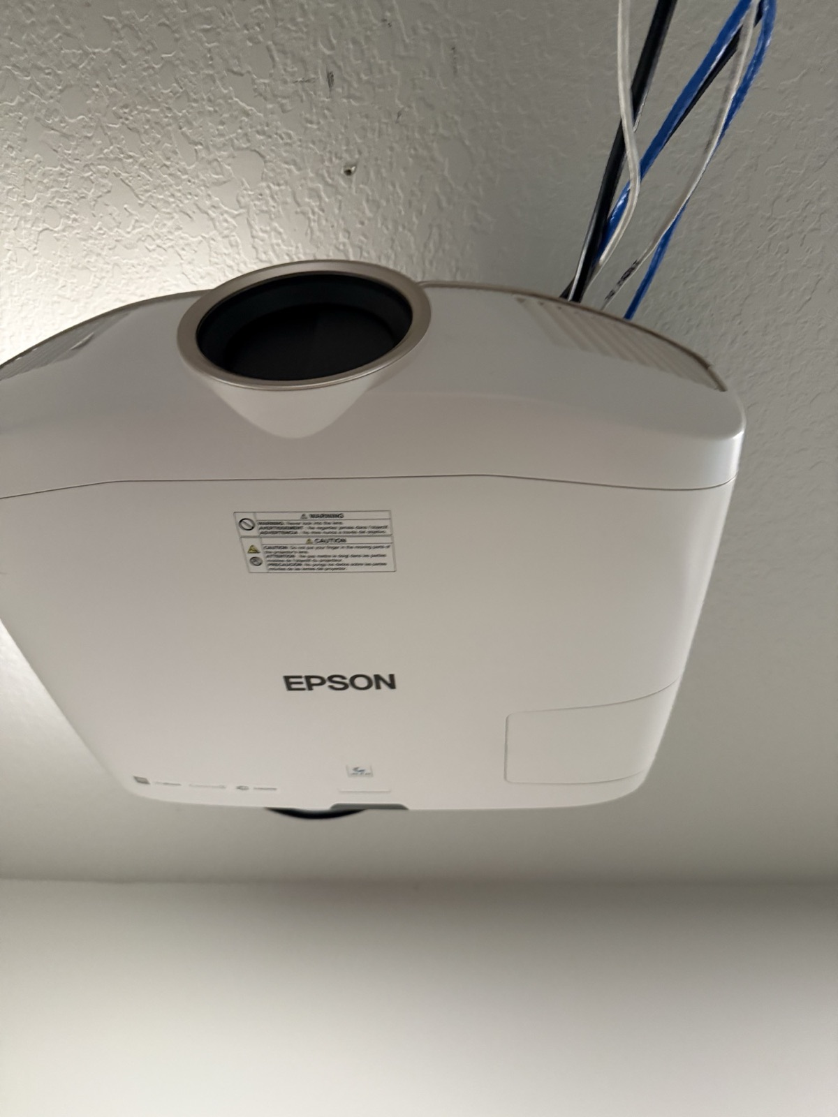 Epson projector ceiling-mounted and inverted, with its cable bundle entering the ceiling.