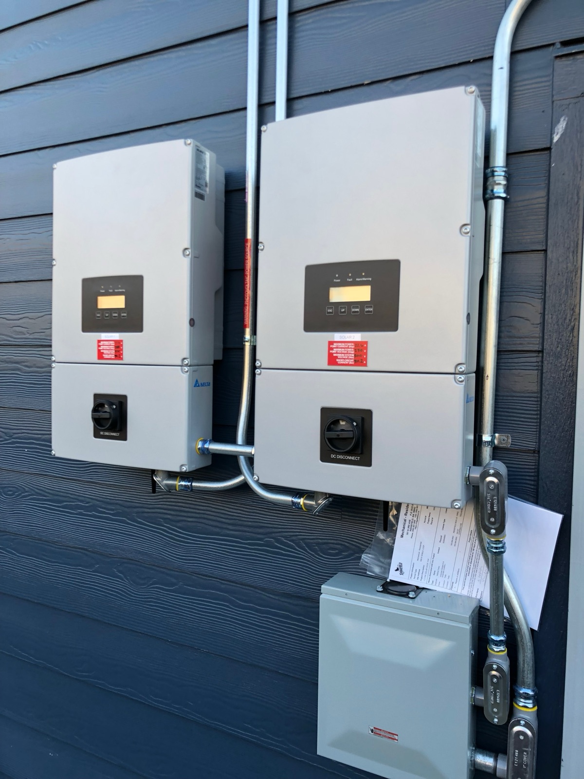 Two Delta string inverters labelled SOLAR 1 and SOLAR 2, each with an integrated DC disconnect below it.