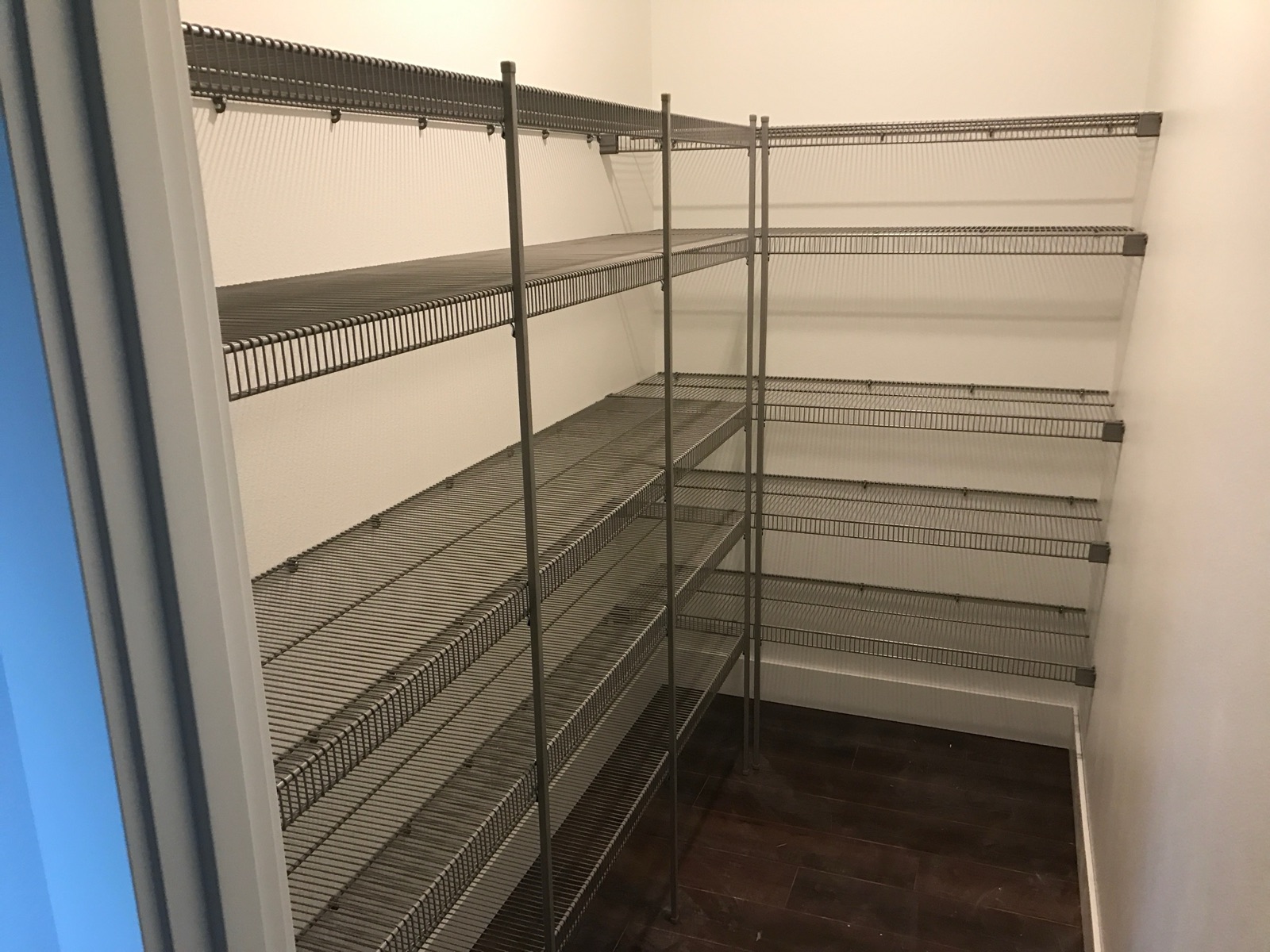 Empty walk-in pantry with tiered wire shelving.